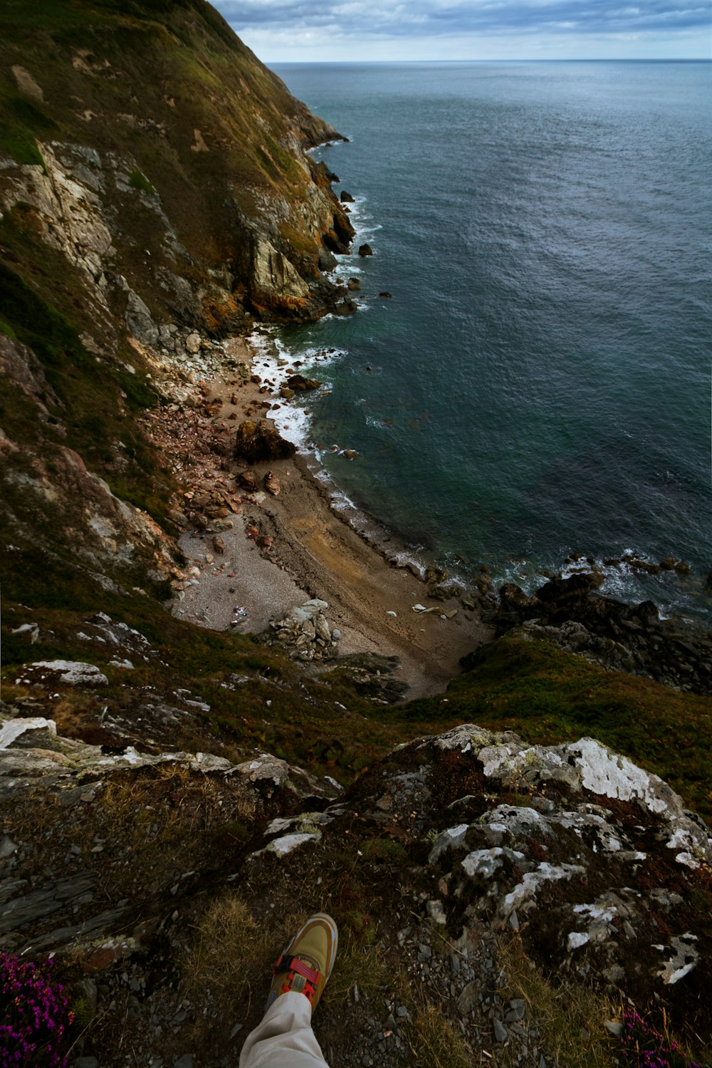 a person's feet on a rocky cliff above a body of water