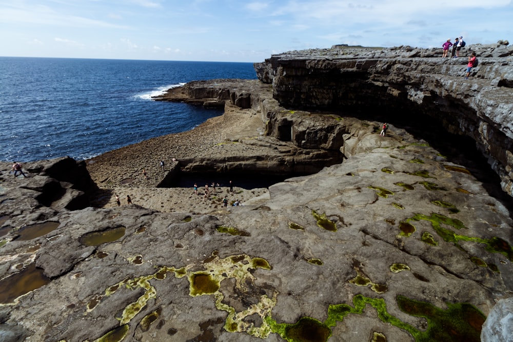 a rocky beach with people walking on it