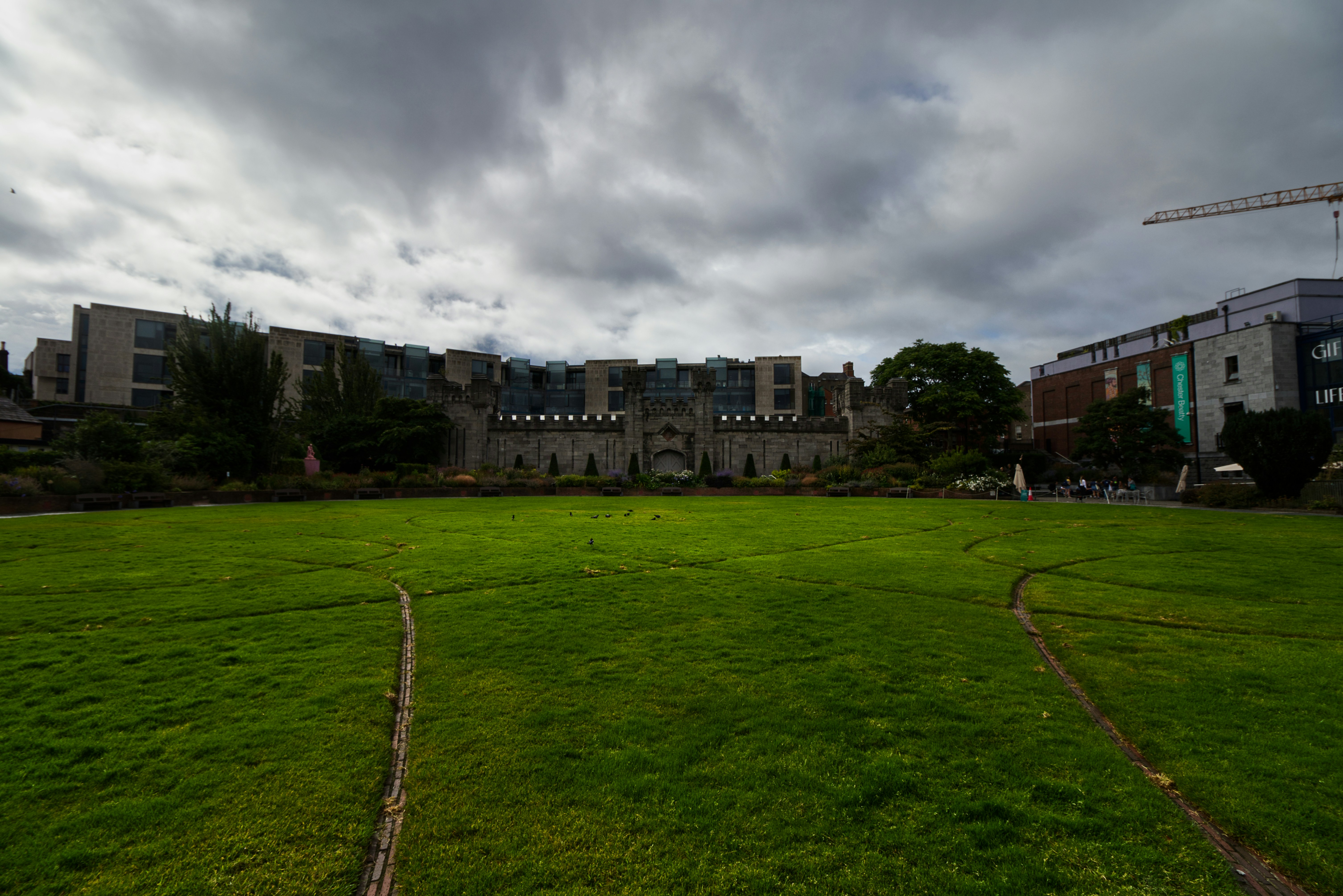 a large green field with buildings in the background