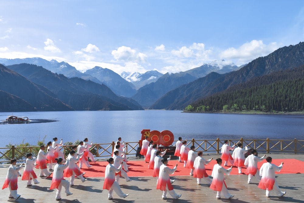 a group of people in white karate uniforms on a dock by a lake