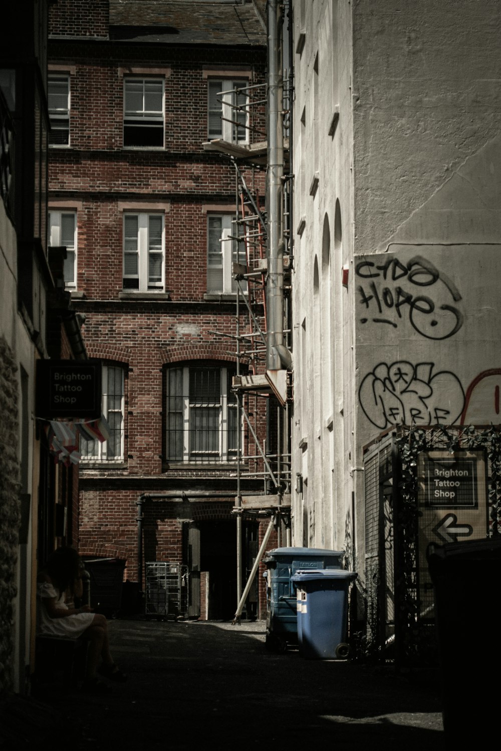 a person sitting on a bench next to a building with graffiti on it
