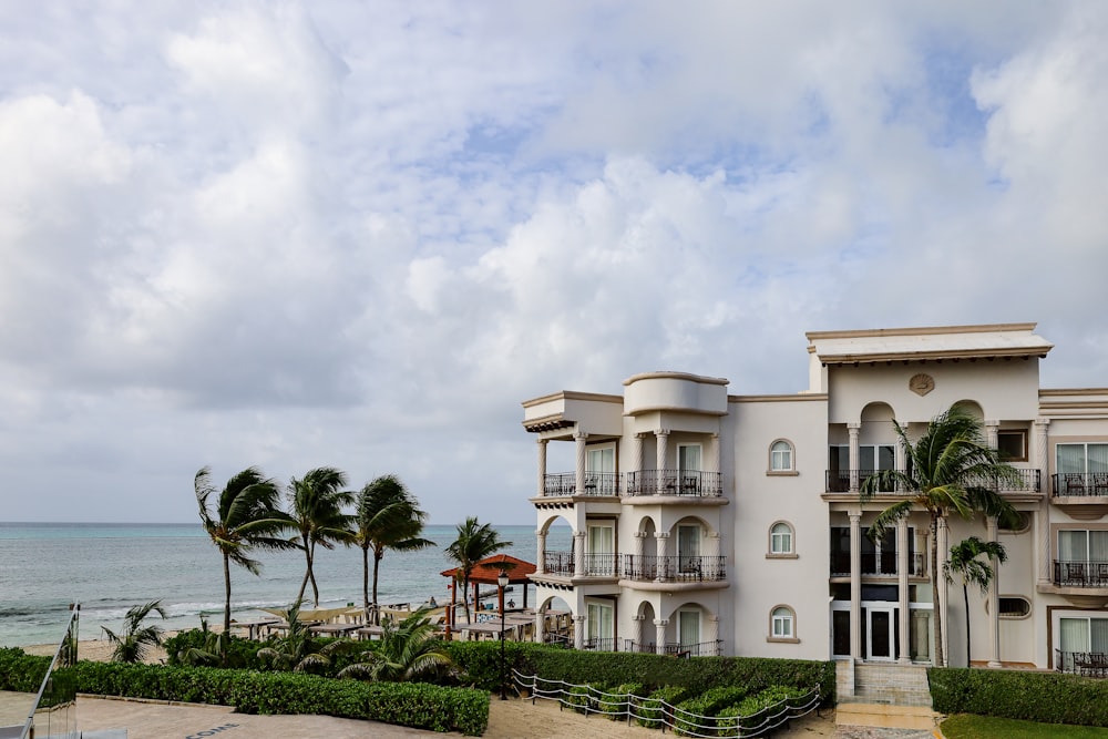 a building with palm trees and a body of water in the background