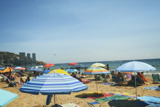 A lively family enjoying the sunny beach and attractions on Sentosa Island with colorful umbrellas.