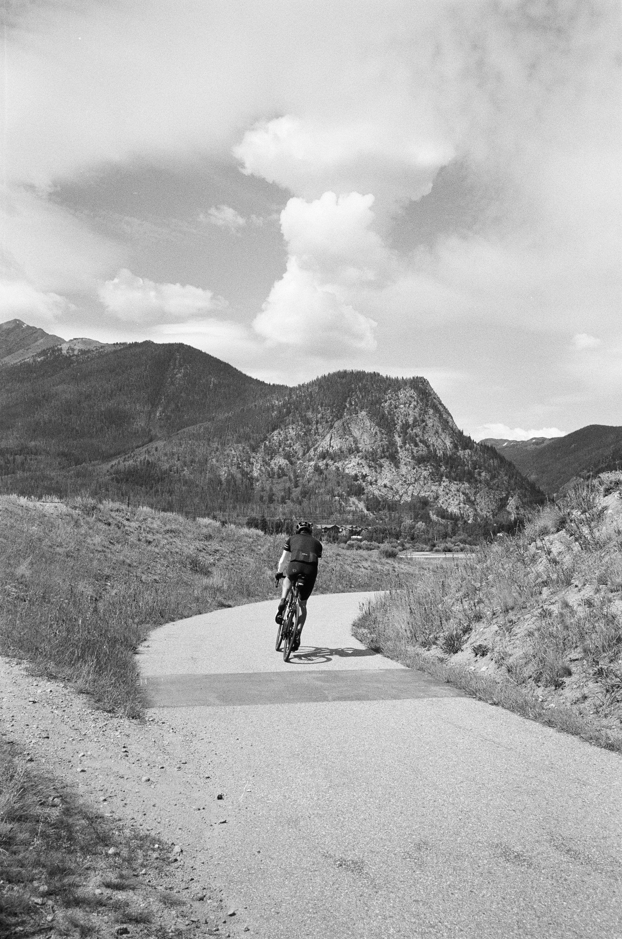 a man riding a bicycle on a road in the mountains