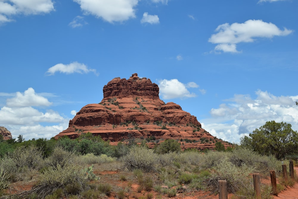 a large rock formation in the middle of a field with Bell Rock in the background