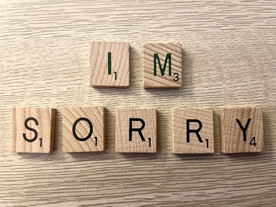 A simple, handwritten note with the words 'I'm sorry' on a wooden table.