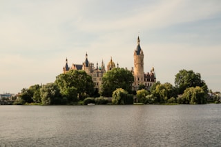 a castle on a hill by a body of water with Schwerin Palace in the background