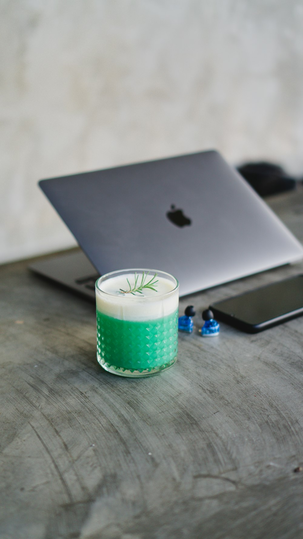 a green cup next to a laptop