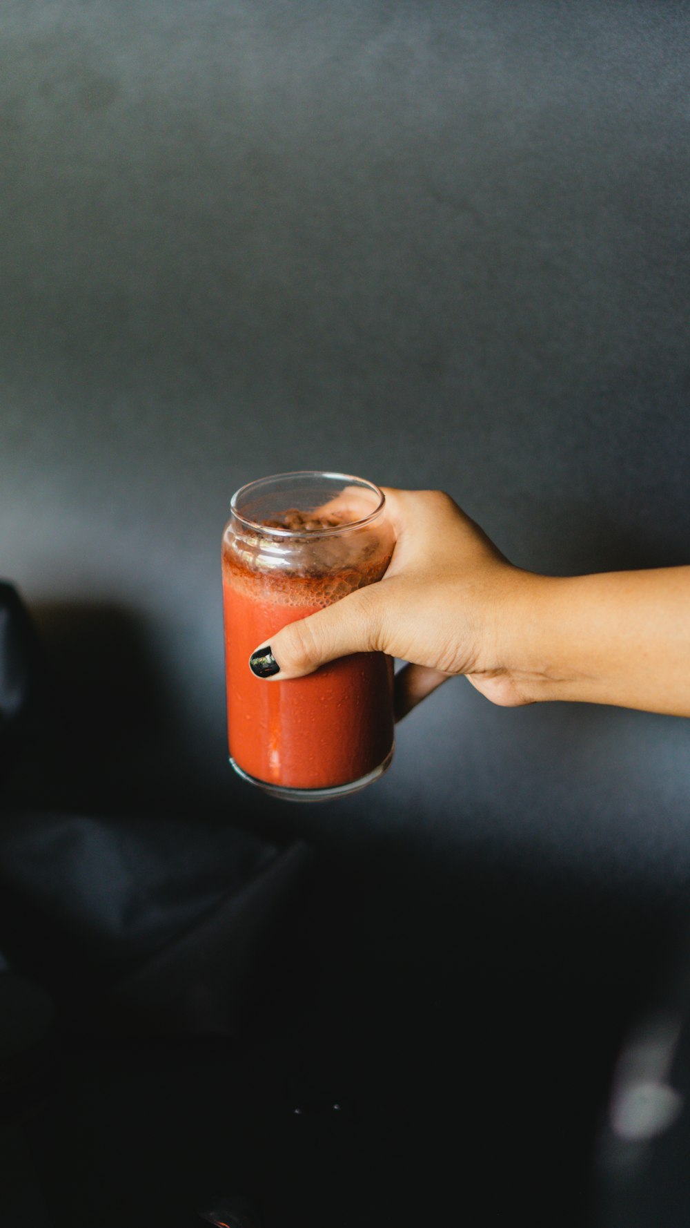 a hand holding a glass of liquid