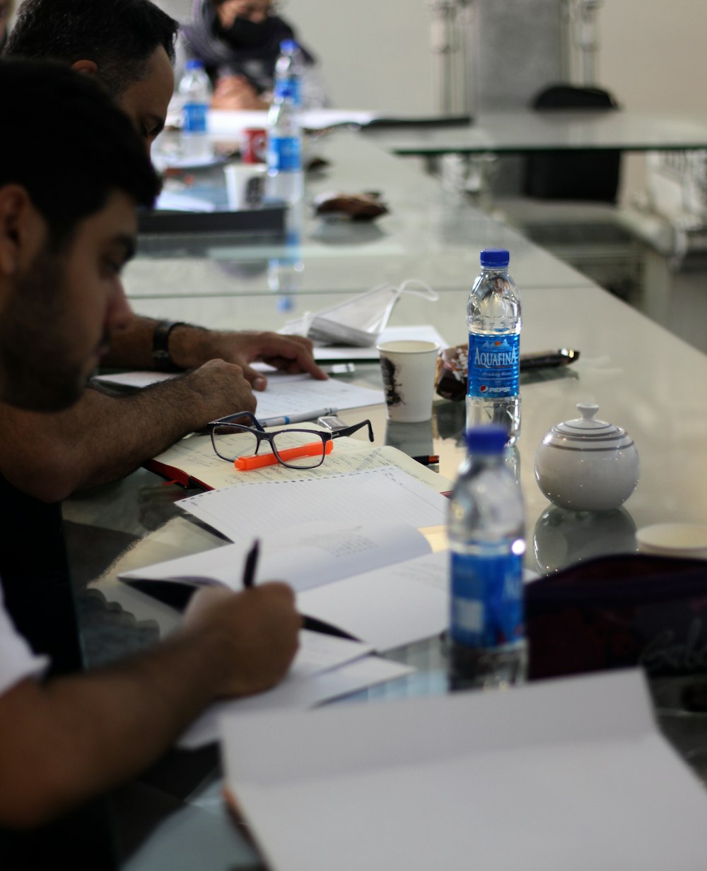 a man sitting at a table with a pen and paper and water bottles