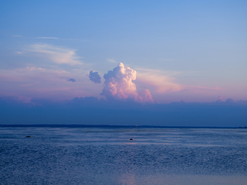 a body of water with clouds above it