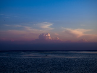 a body of water with clouds above it