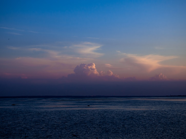 a body of water with clouds above it