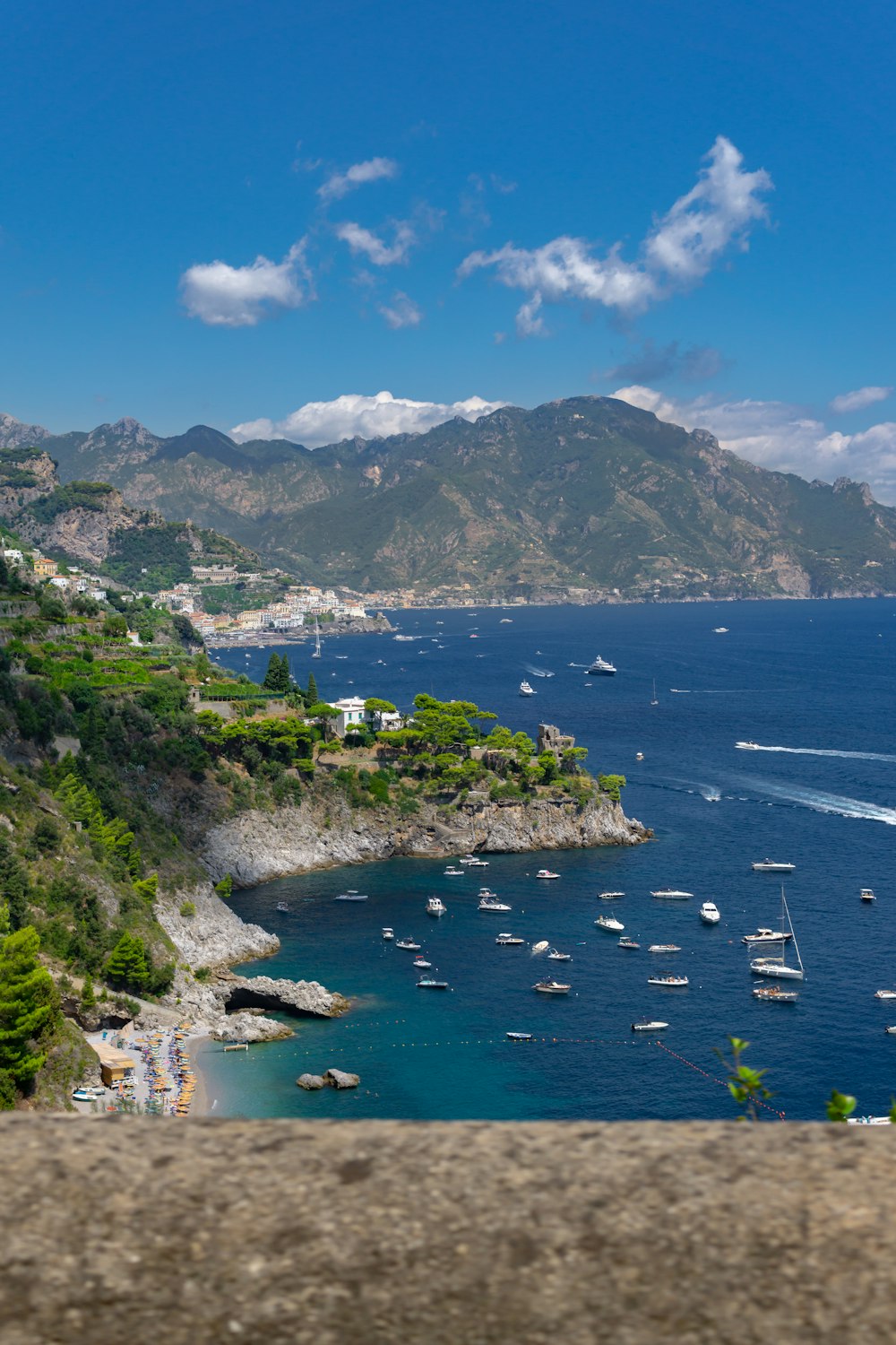 a body of water with boats in it and mountains in the back