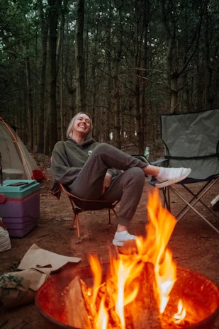 A cozy, weather-resistant jacket draped over a camp chair beside a glowing campfire.