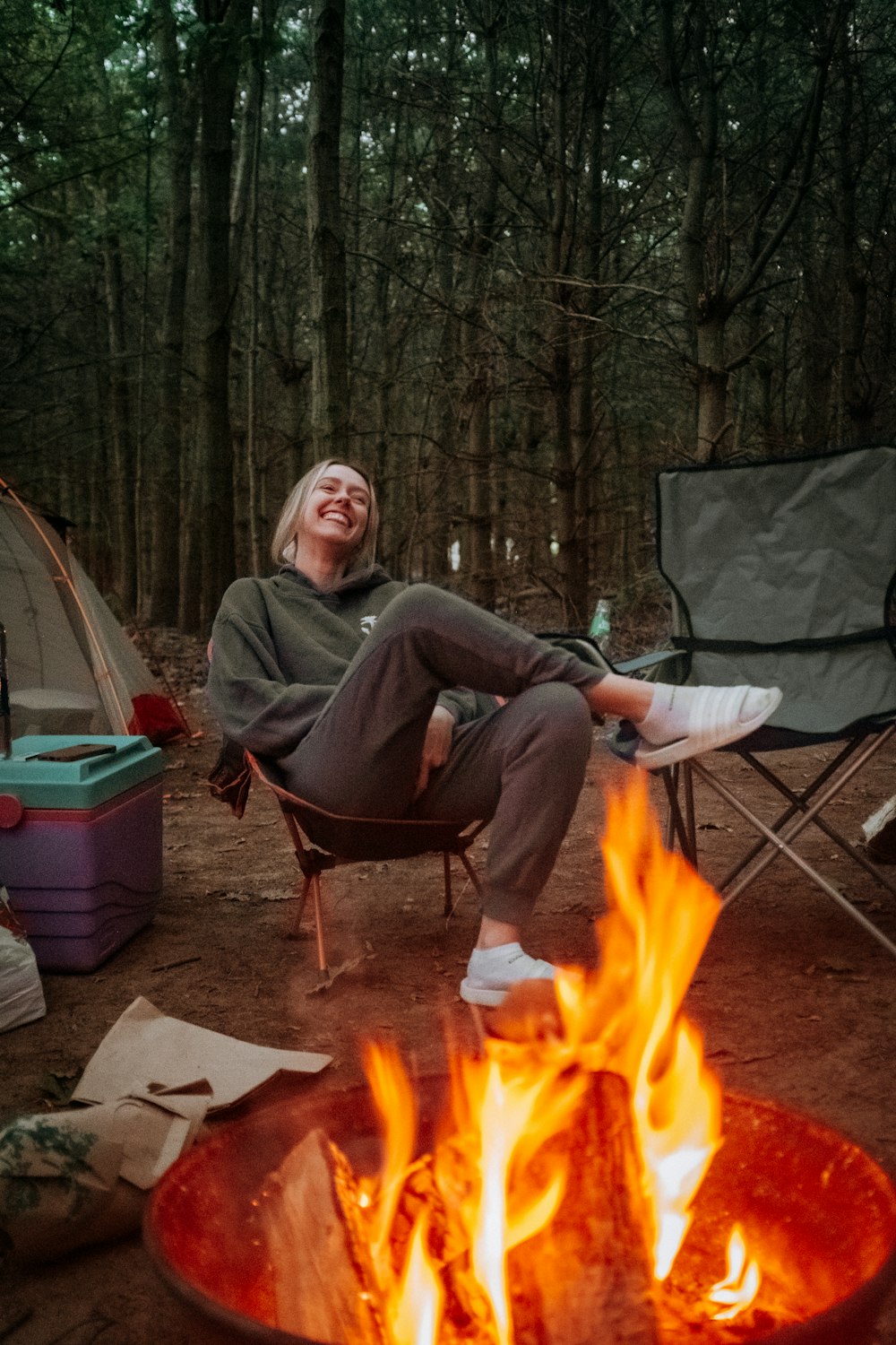 a person sitting on a chair by a campfire