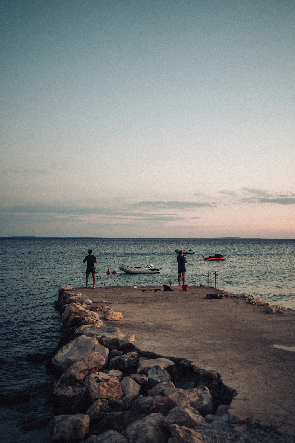 a group of people fishing on a rocky beach