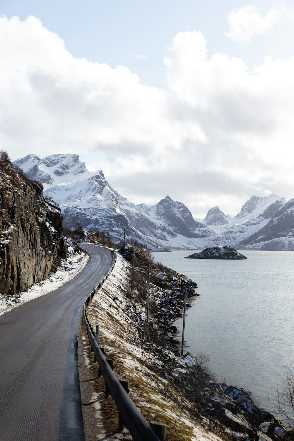 a road next to a body of water with mountains in the background