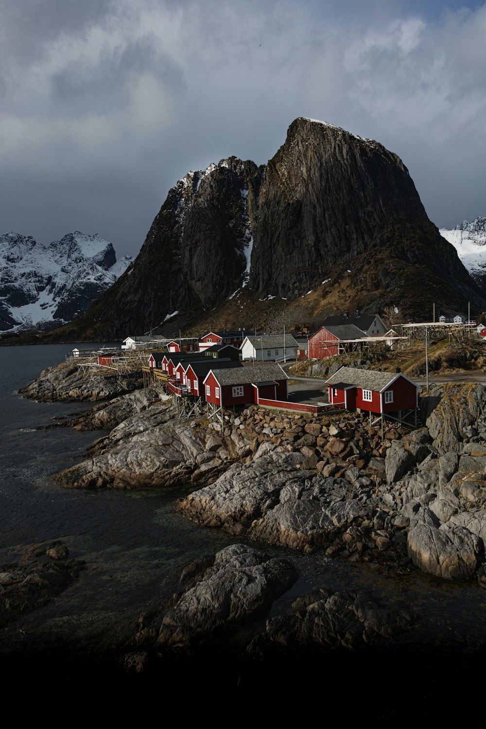 a group of buildings by a body of water with mountains in the background