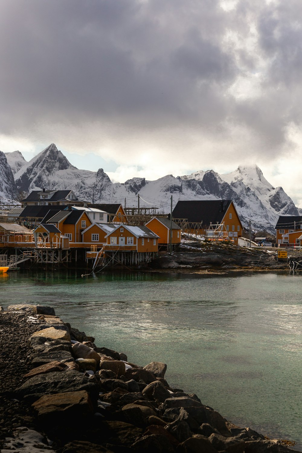 a group of houses by a body of water with mountains in the background