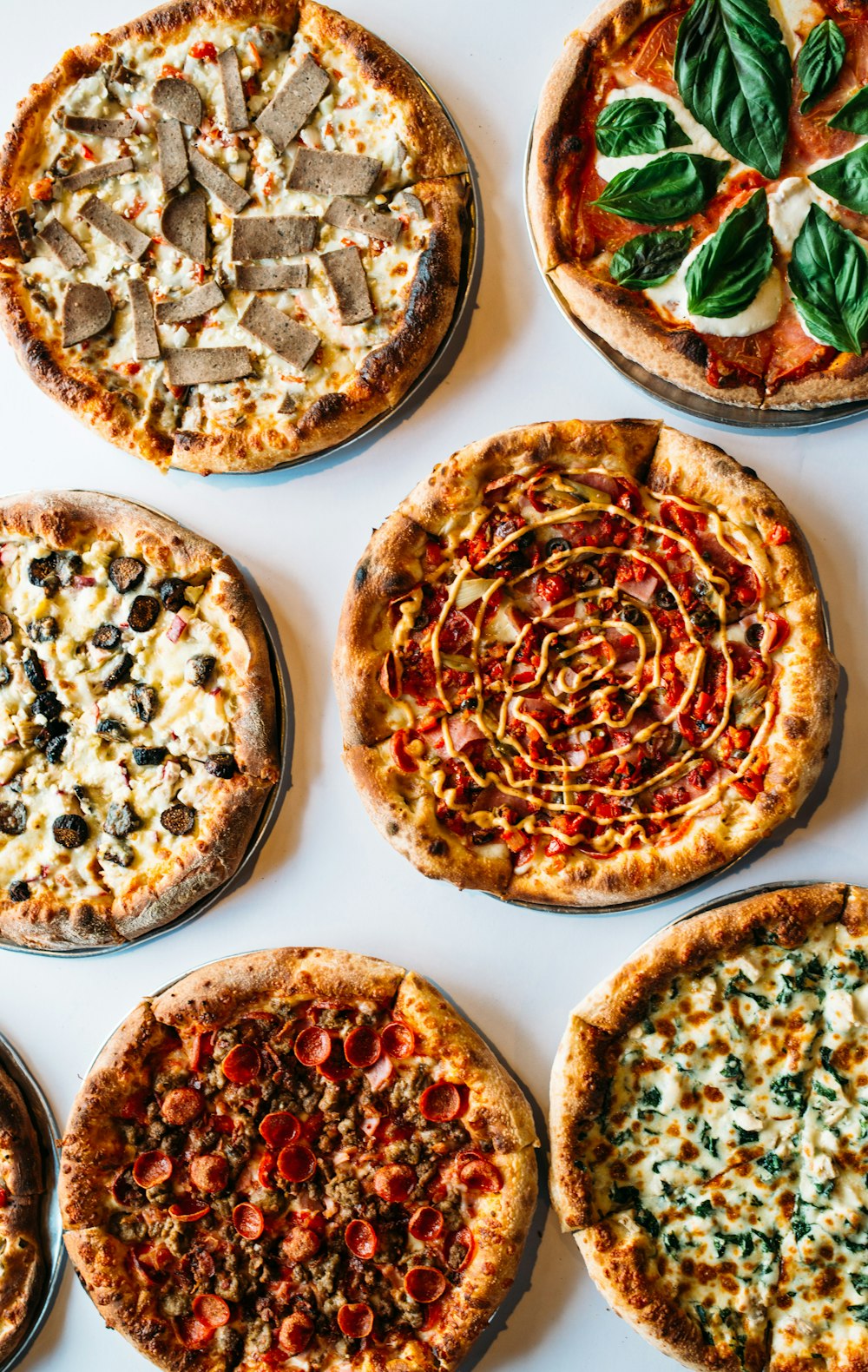 a group of pizzas with mushrooms and olives