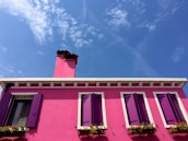 A vibrant painted house standing strong under a bright blue Florida sky.