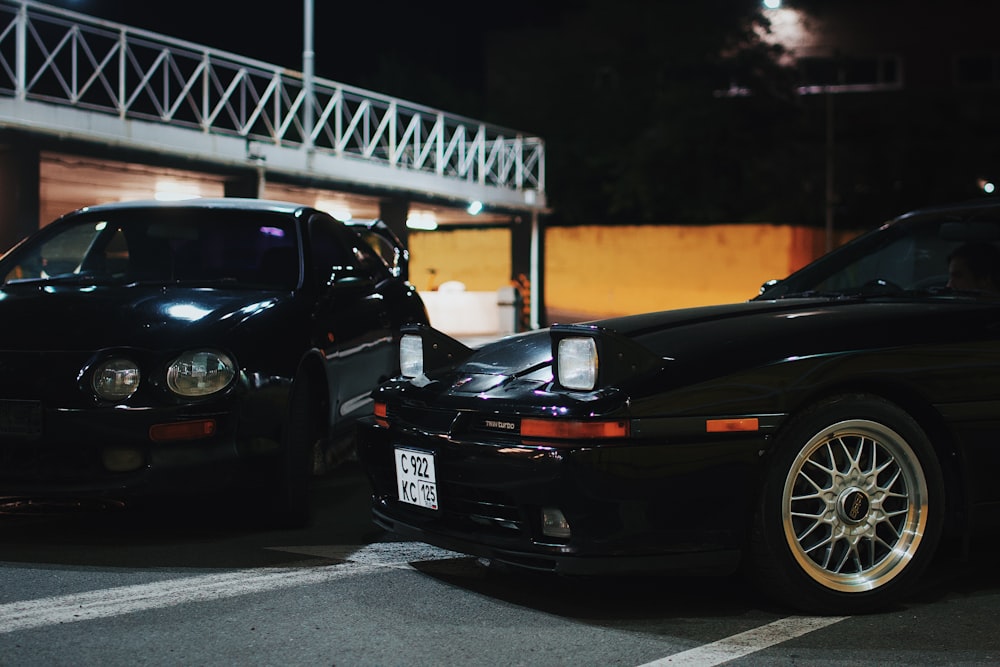 a couple of cars parked in a parking lot at night