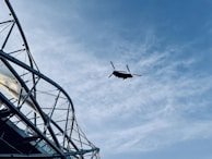 A helicopter is seen flying in the clear sky, with visible steel framework structure on the left side.