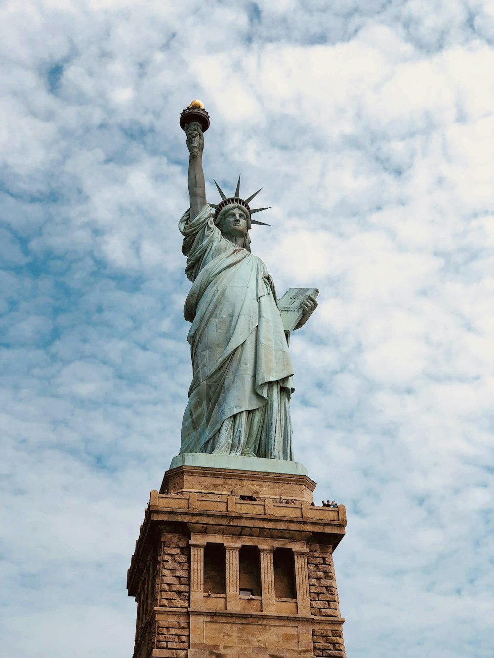 a statue of a person holding a torch with Statue of Liberty in the background