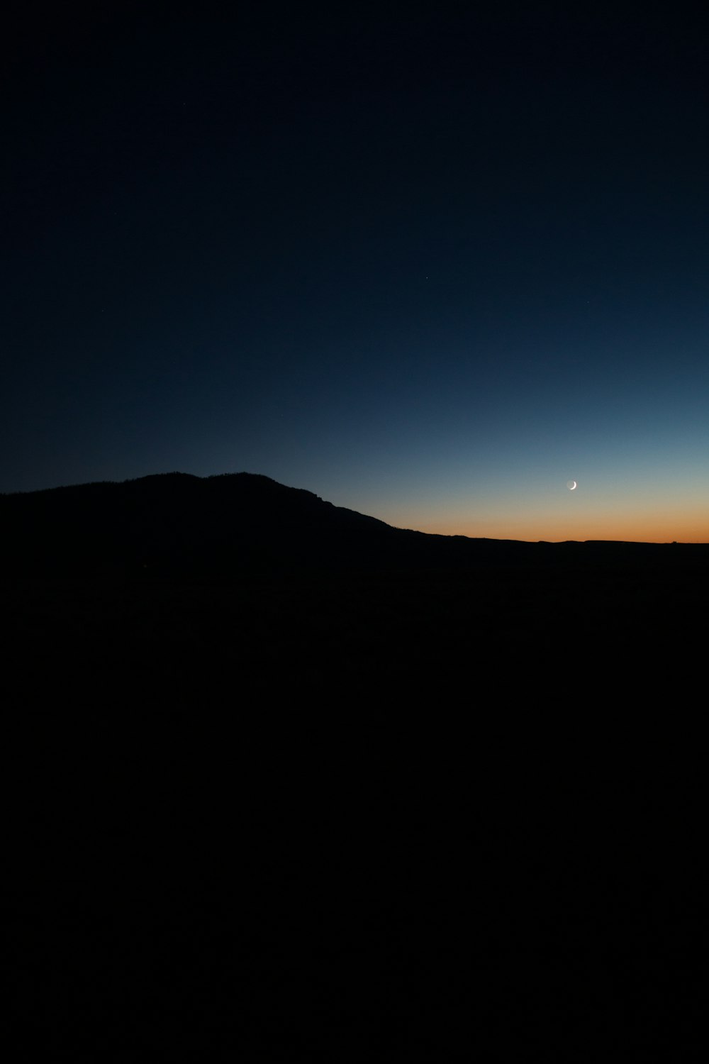 a dark hill with a blue sky