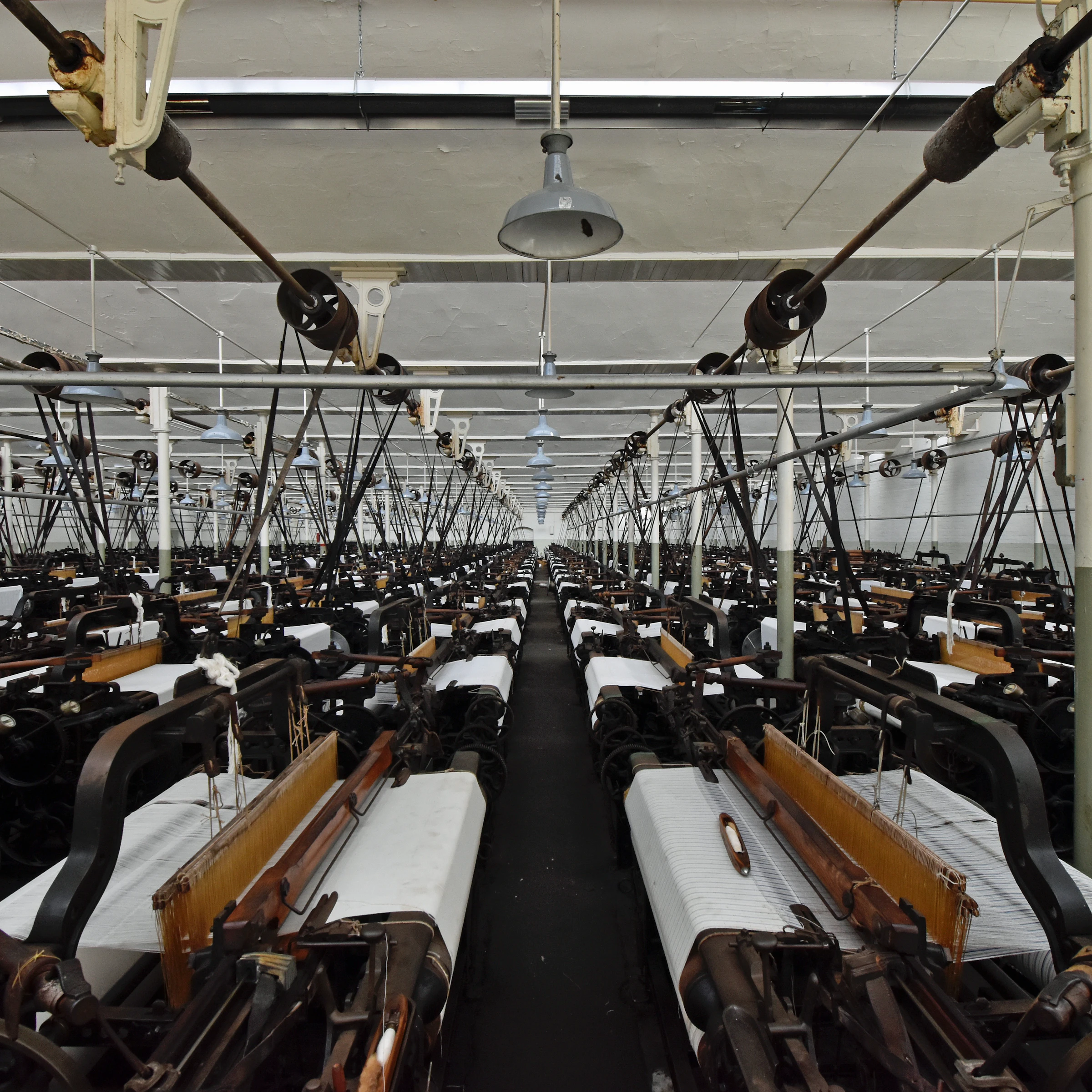 A long aisle of knitting machines inside a textile mill