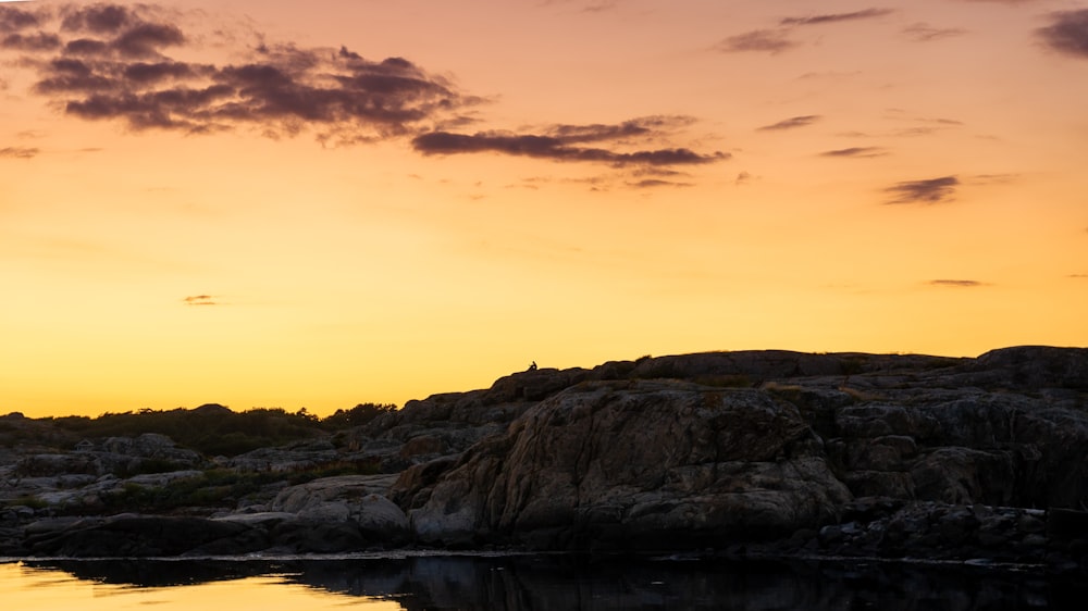 Una spiaggia rocciosa con un tramonto