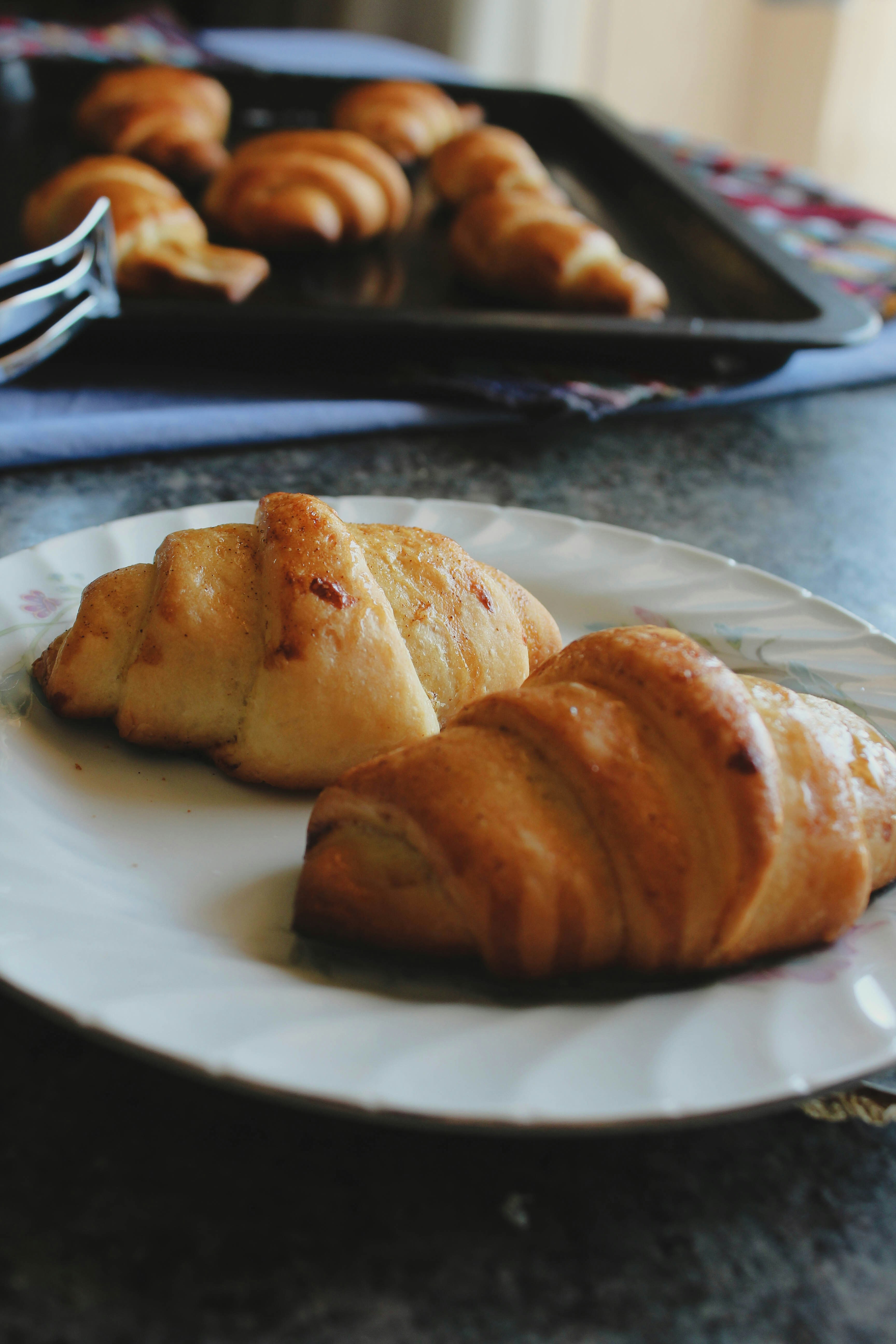 Croissante aurii proaspăt coapte pe o tavă de lemn în lumina dimineții
