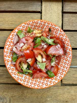 A vibrant salad with arugula, parmesan, and cherry tomatoes in a ceramic bowl.