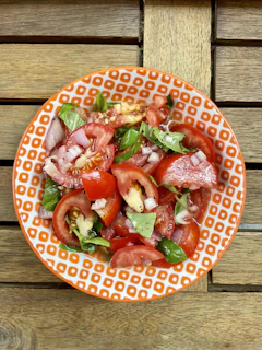 A colorful bowl of fresh summer salad with cherry tomatoes, cucumbers, and herbs