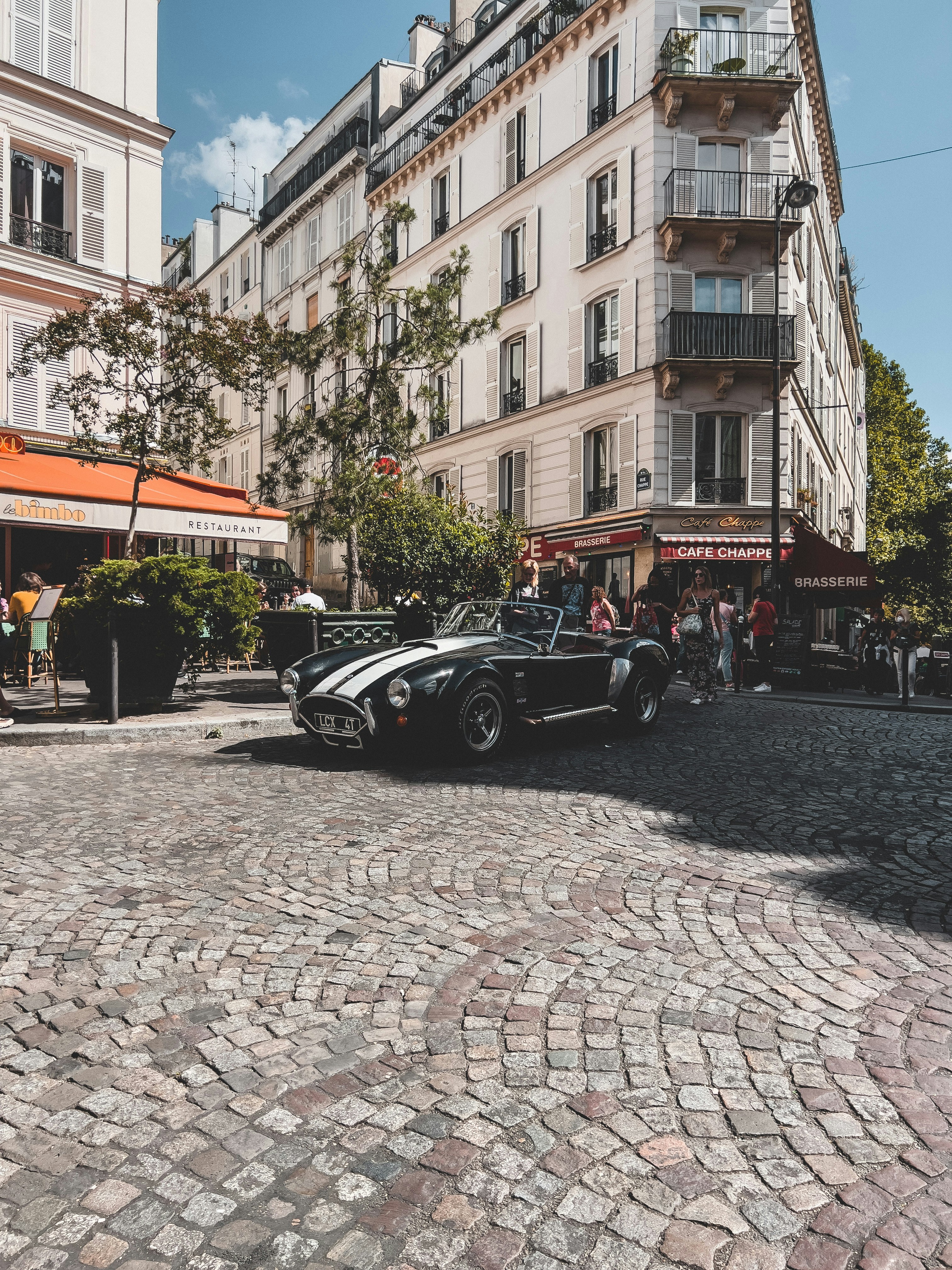 a car parked on a cobblestone street in front of a building