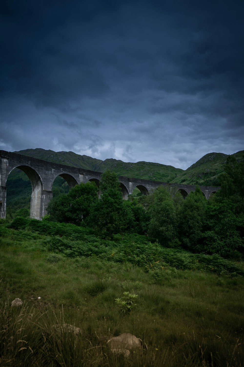 a stone bridge over a grassy hill