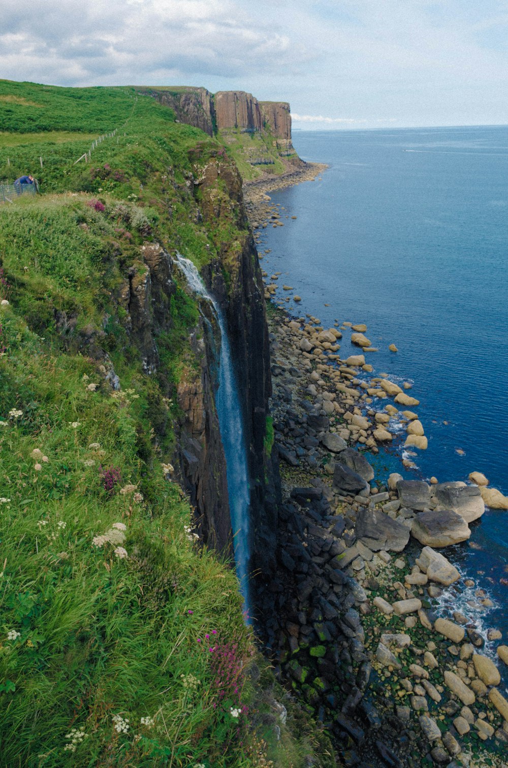 a rocky cliff side with a body of water and a large cliff