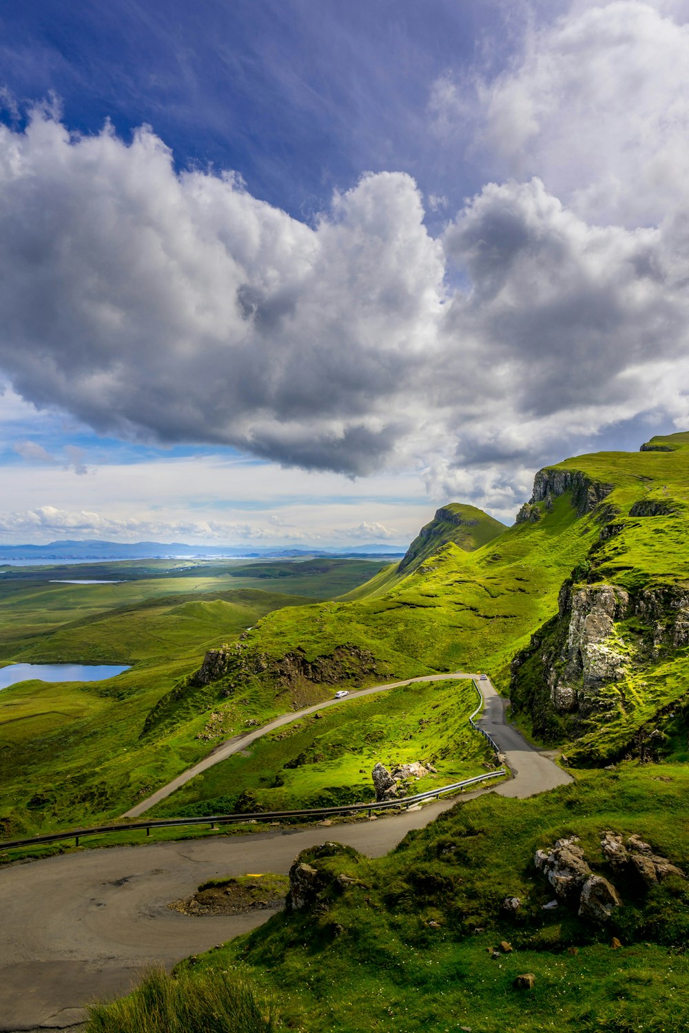 a road going through a valley with Quiraing in the background