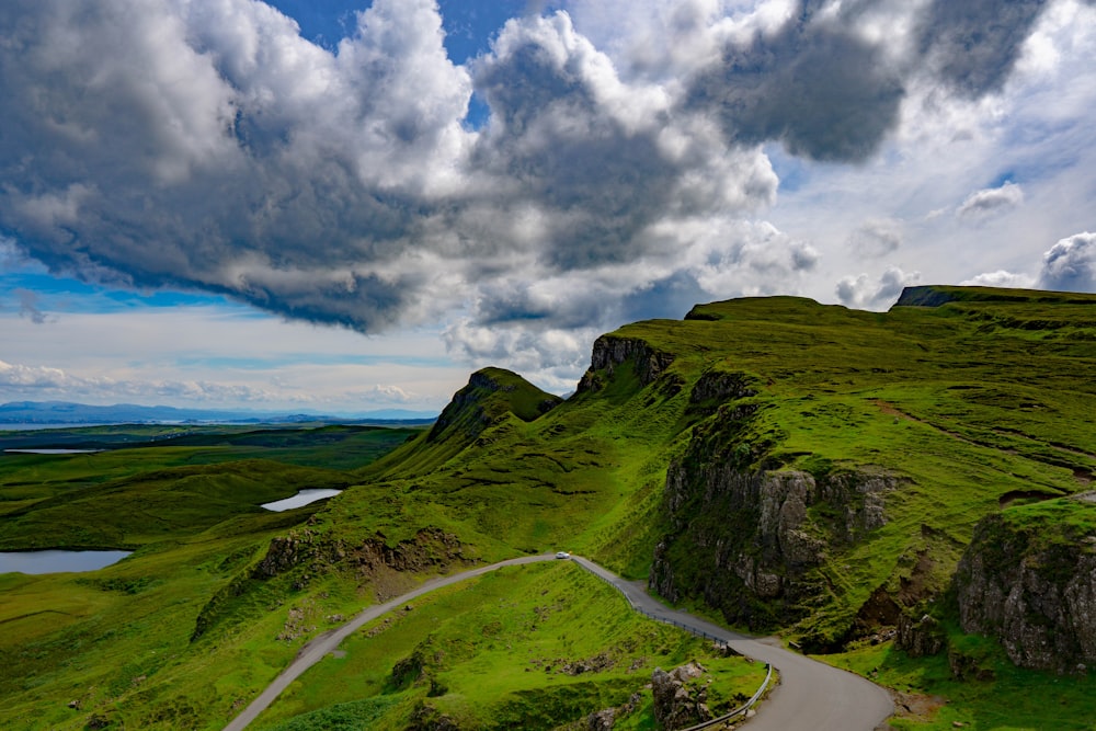 a winding road through a valley with Quiraing in the background