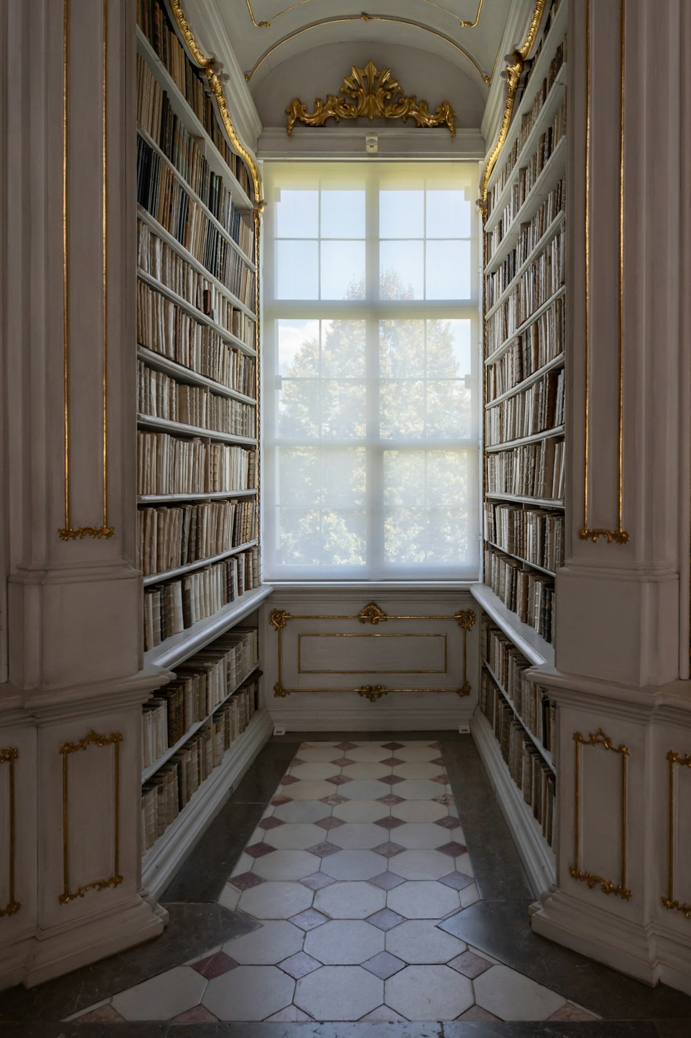 a room with a window and bookshelves