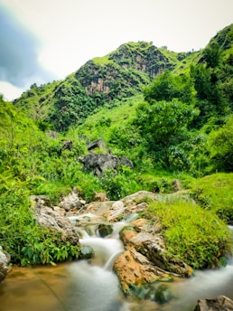 A serene landscape showcasing a mining site surrounded by lush greenery and mountains.