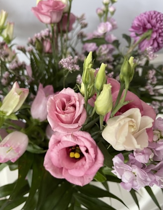 A close-up of a colorful, freshly arranged bouquet showcasing roses, lilies, and greenery.
