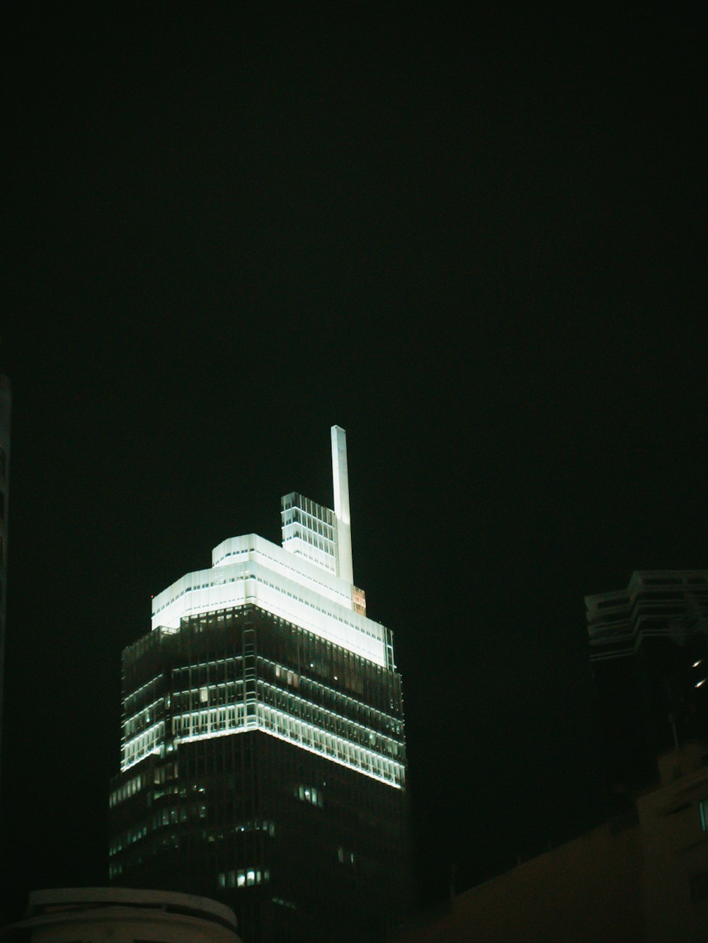 Un edificio alto con una parte superior puntiaguda por la noche