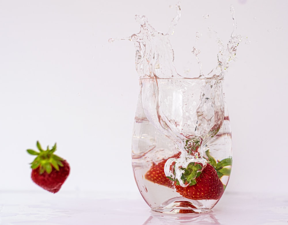 a strawberry splashing into a glass of water