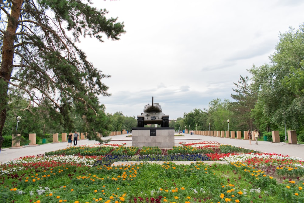 a large garden with flowers and a statue in the middle