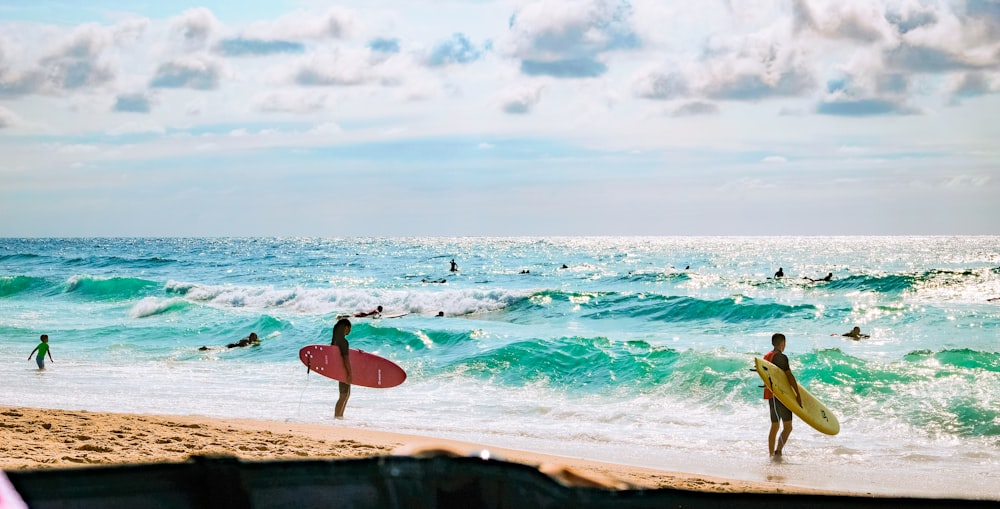 surfers carrying their boards on the beach