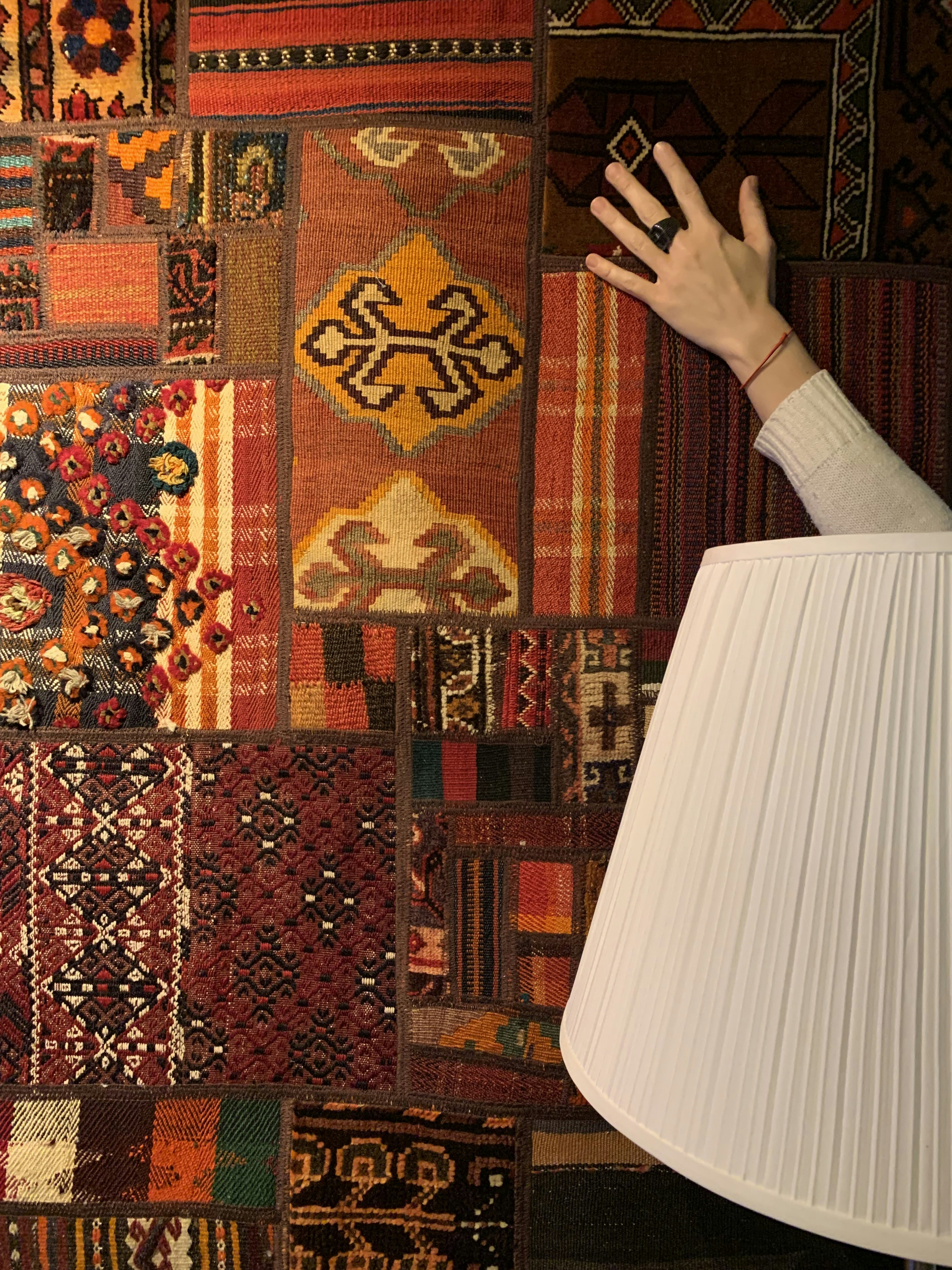 Artisan hand drawing carpet design on graph paper with pencil, geometric floral pattern taking shape, warm desk light