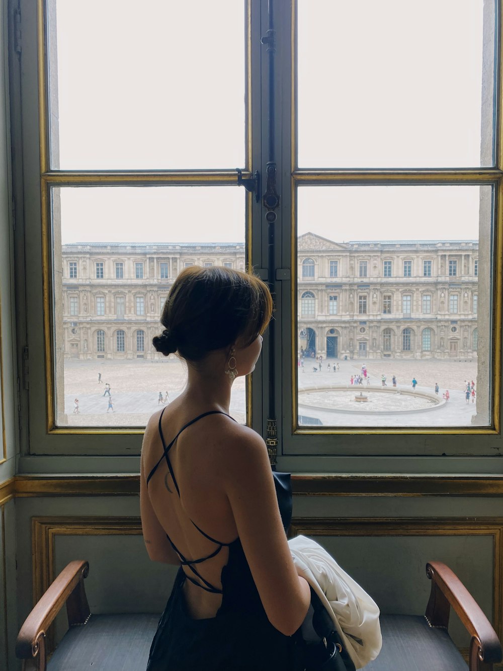 a woman sitting on a bench looking out a window