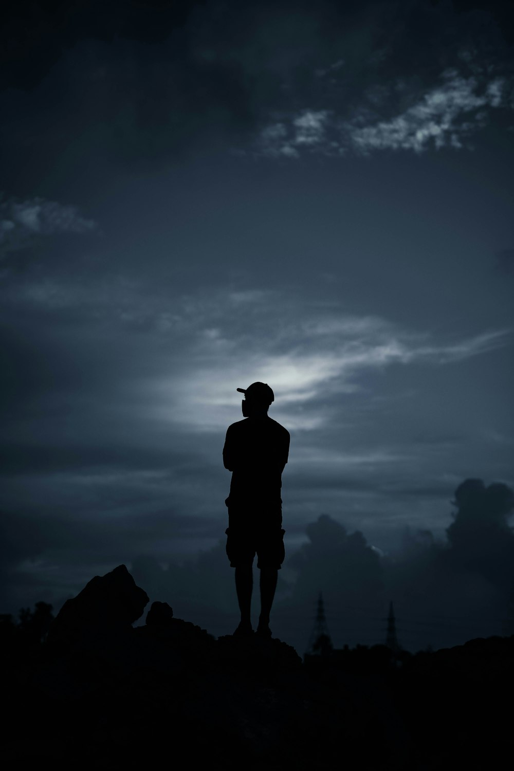 a silhouette of a person standing on a hill with a cloudy sky